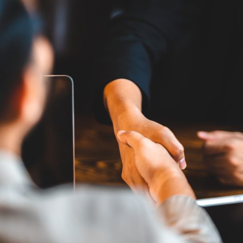 Closeup of unidentified young professionals and business people shaking hands after signing the deal and at the start of a new meeting to discuss company growth and strategy for future