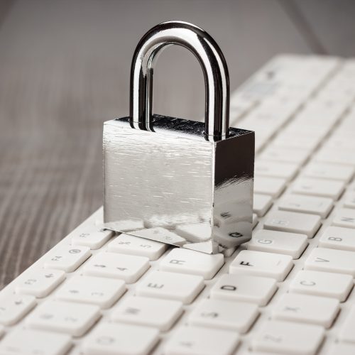 padlock and white computer keyboard on the wooden office table. privacy protection, encrypted connection concept
